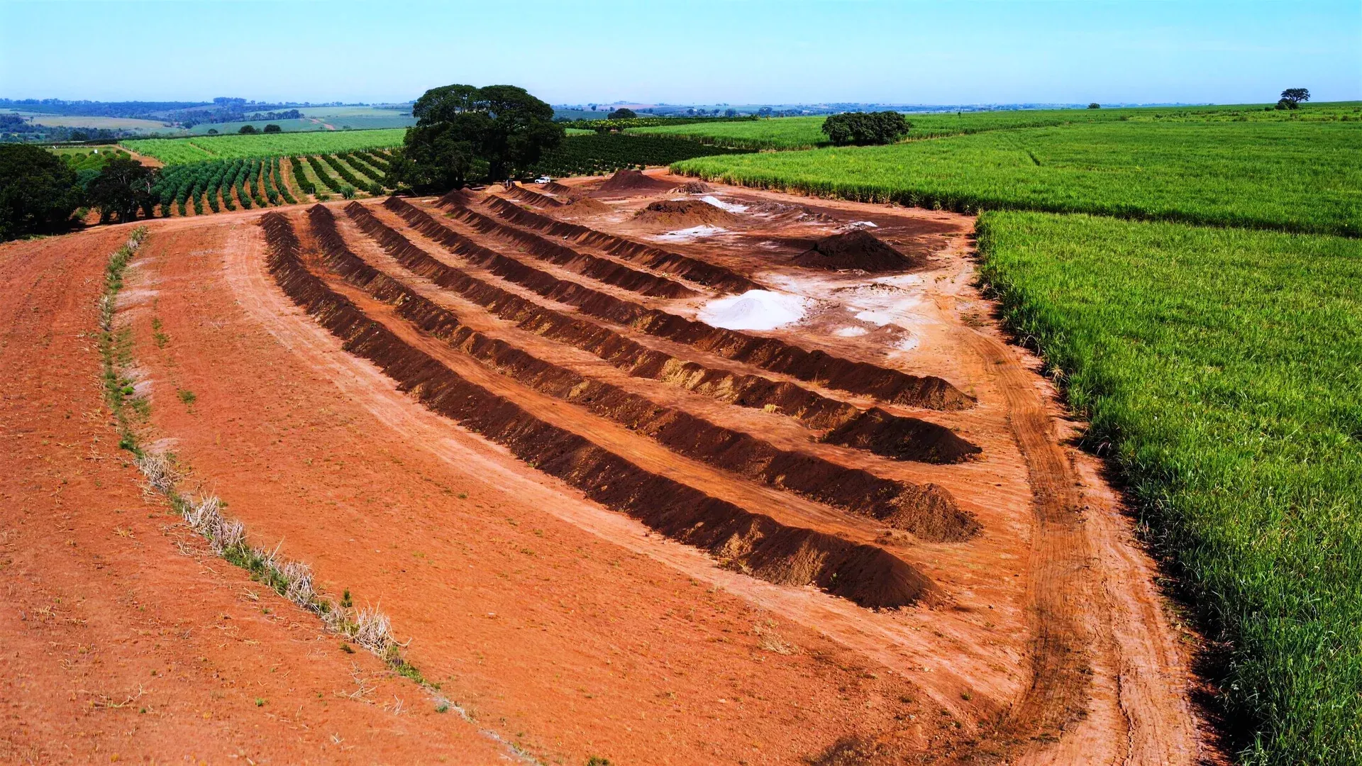 Pátio de compostagem visto de cima, leiras entre a lavoura